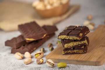 Gourmet chocolate mixed with crunchy kadaif pistachio pieces is beautifully presented on a wooden board, making a perfect treat in Dubai's culinary scene.