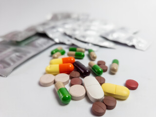 Assorted pills and capsules with blister packs on white background