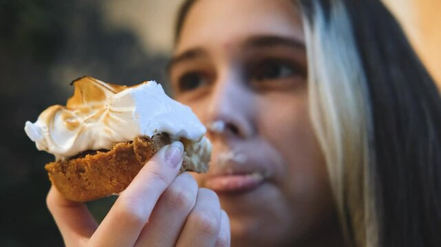 Teen girl eats white cream cake with appetite, enjoys food