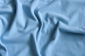 Light blue fabric texture background showing soft ripples and folds