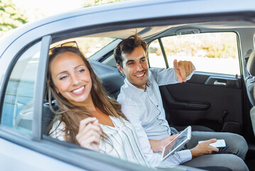 Couple in back seat of car looking out the window.