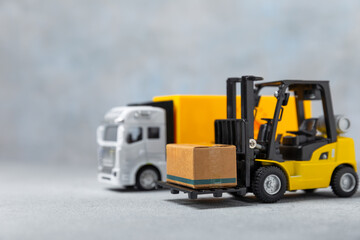 Yellow forklift and yellow truck on bright background. Logistics concept. Logistics and supply chain management of online shopping. Delivery of goods or products to the store worldwide. Cardboard box.