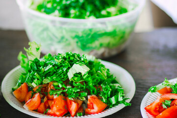 Close-up of fresh cucumber and tomato salad on a white plate placed on a natural wooden table, with focus on vibrant colors and texture of the vegetables.

