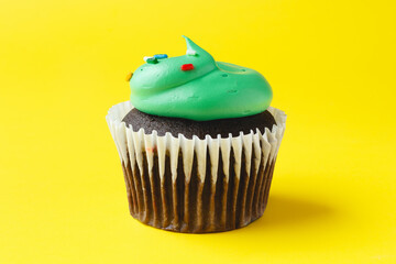 Chocolate cupcake with green frosting on yellow