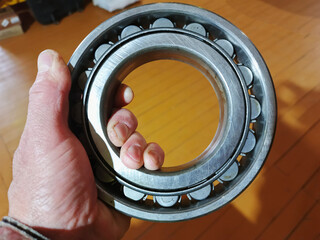 The hand holds a large metal bearing.The hand holds a large metal bearing.