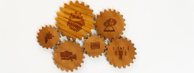 A creative arrangement of wooden gears featuring engraved icons that represent teamwork and...