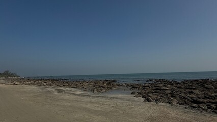 Expansive View of a Rugged Rocky Shoreline at Low Tide Meeting the Calm Blue Water and Clear...