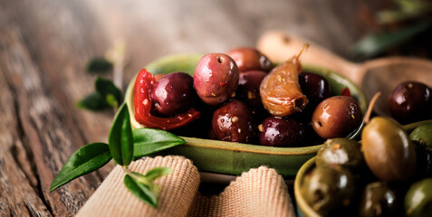Olives, homemade marinated colorful olives with herbs, garlic and spices on rustic table, close up. Healthy Mediterranean vegan food, macro shot