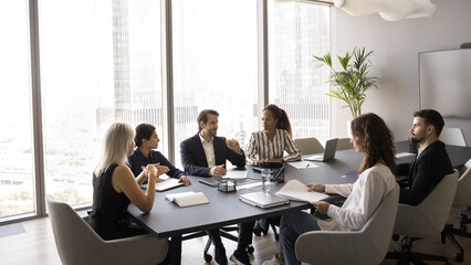 Business negotiations. Multicultural diverse executives team department staff stakeholders partners meet at table in office boardroom for briefing discuss paper contract finance report plan investment