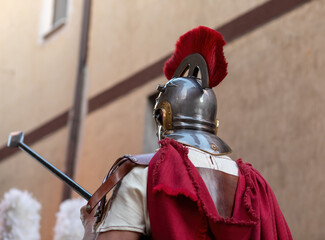 Roman centurion wearing helmet and red cape holding spear
