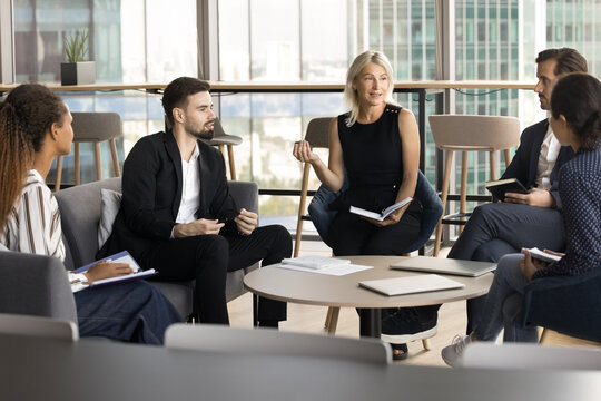 Group education. Middle aged woman professor teacher coach hold learning event training seminar workshop for diverse multiethnic student team at cozy modern meeting room give knowledge lead discussion