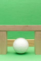 Still life with wooden blocks and a a plastic foam ball on green background	
