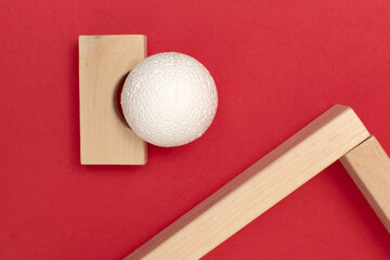 Still life with wooden blocks and a a plastic foam ball on red background	