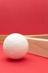 Still life with wooden blocks and a a plastic foam ball on red background	