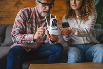 senior man and adult woman set up surveillance security camera