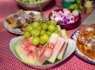 fruits, watermelon slices and grapes in the plate on the table, together with panettone sweet bread and chocolate easter eggs