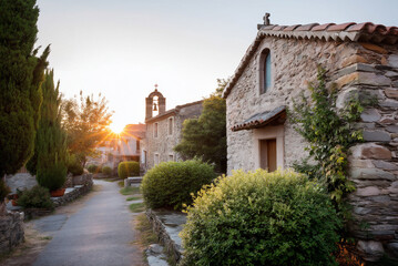 Fototapeta premium simple village church with stone walls and bell tower at sunrise.