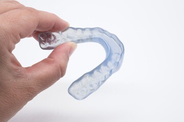 Doctor holding a clear dental night guard or mouthguard designed to protect teeth from grinding, promoting oral health and hygiene for patients