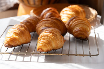 A cooked golden color of traditional French croissants in a baking tray. It's viennoiserie of Austrian origin. Made with a yeast leavened dough that has been laminated with butter in multiple layers.
