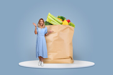 A cheerful customer stands beside a large paper bag filled with fresh fruits and vegetables,...