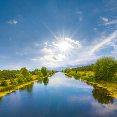 long irrigational channel with forest on coast at the sunny day