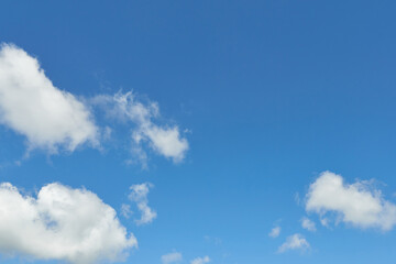 White fluffy clouds in the sky. Blue sky and cloud cover on a sunny summer day. Empty background, copy space