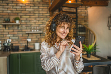 cheerful woman use mobile phone and headphones listen music and dance