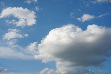 White fluffy clouds in the sky. Blue sky and cloud cover on a sunny summer day. Empty background, copy space
