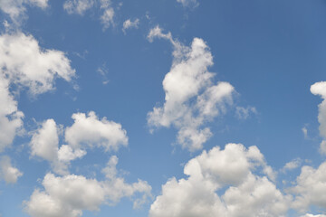 White fluffy clouds in the sky. Blue sky and cloud cover on a sunny summer day. Empty background, copy space