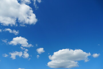 White fluffy clouds in the sky. Blue sky and cloud cover on a sunny summer day. Empty background, copy space