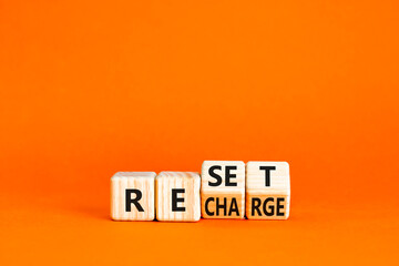 Reset and recharge symbol. Concept words Reset Recharge on beautiful wooden block. Beautiful orange...