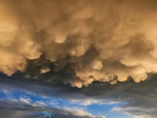 Storm clouds on sunset. Light in the dark and dramatic storm clouds. Background of storm clouds before a thunderstorm. Mammatus clouds
