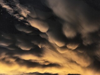 Storm clouds on sunset. Light in the dark and dramatic storm clouds. Background of storm clouds before a thunderstorm. Mammatus clouds