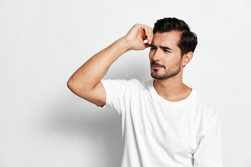 Thoughtful man white t-shirt looking aside touching forehead isolated on gray background emotional...