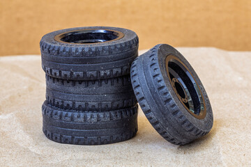 Pile of toy car tires with black rims, set of wheels, 3 tires stacked storage, one tire leaned against the others