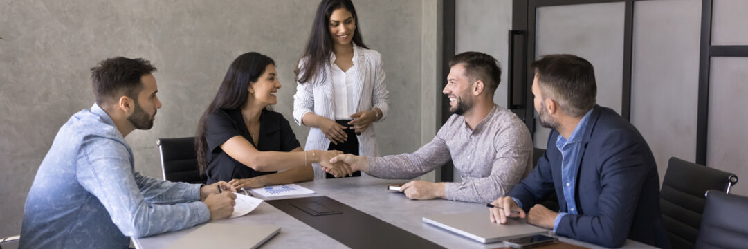 Smiling business partners shaking hands closing commercial profitable deal, finish formal meeting in conference room of modern office. Conclude partnership, procurement, merge, successful negotiations