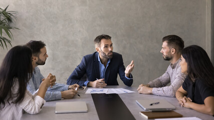 Mature businessman lead negotiations with partners or shareholders at conference table, provide...