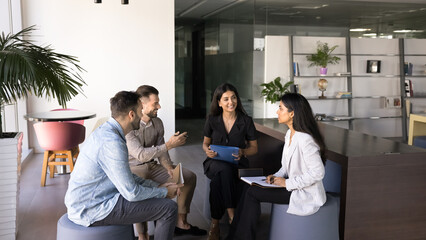 Employees gather in modern office space, engaged in interactive and collaborative discussion,...
