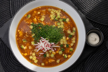 Okroshka, a traditional Russian cold soup made with kvass, features diced vegetables like potatoes, cucumbers, and radishes, garnished with fresh herbs and sour cream