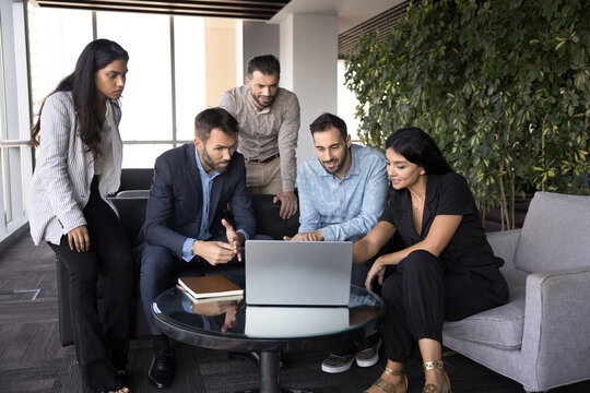 Productive workflow using modern tech of five diverse employees gather in office lobby area, look at device screen, analyze data, reviewing report, going over key metrics or visual aids. AI, business