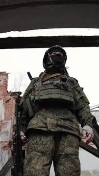 Infantry soldier stands firmly amidst the ruins, clad in full combat gear military uniform, helmet, and bulletproof vest. Behind him, a war-torn house bears the scars of a brutal urban battle, the