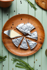 Plate with triangles of tasty processed cheese on green wooden background