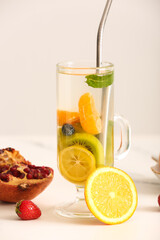 Glass of infused water with different sliced fruits on white table