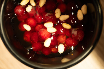 Close up of a black bowl filled with a traditional Altai dessert featuring frozen lingonberries,...