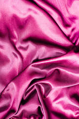Soft and luxurious pink silk fabric lies in gentle folds, showcasing its rich texture and vibrant color.