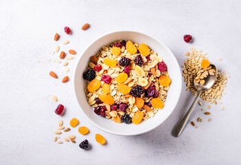 A bowl of granola with fruit and nuts on a table.