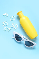 Word SPF with numbers made of sunscreen cream and sunglasses on blue background