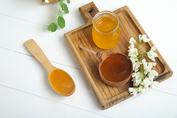 Composition with sweet honey and acacia flowers on light wooden background