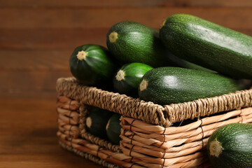 Wicker basket with fresh zucchini on brown wooden background