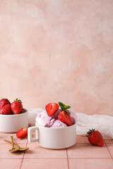 Cup with delicious ice cream, fresh strawberries and mint on pink table